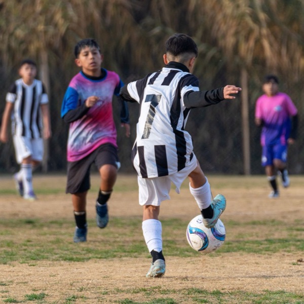 A young soccer player striking the ball in a match